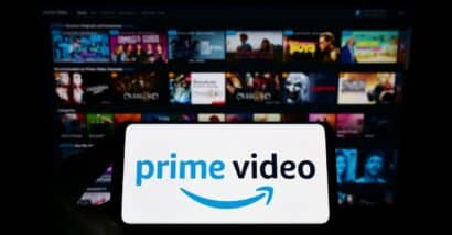 Person holding smartphone with logo of streaming service Amazon Prime Video on screen in front of website. Focus on phone display. Unmodified photo.