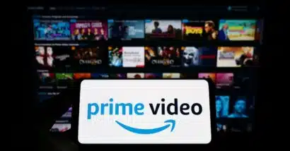 Person holding smartphone with logo of streaming service Amazon Prime Video on screen in front of website. Focus on phone display. Unmodified photo.