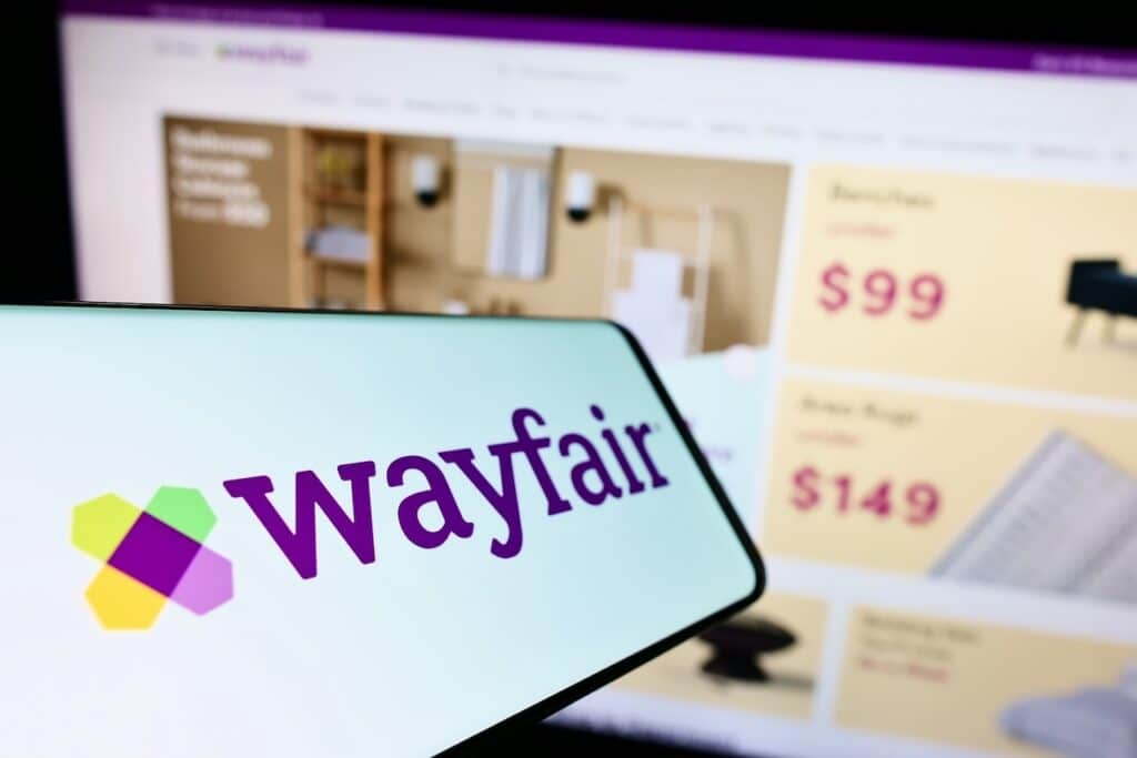 Smartphone with logo of e-commerce company Wayfair Inc. on screen in front of business website.