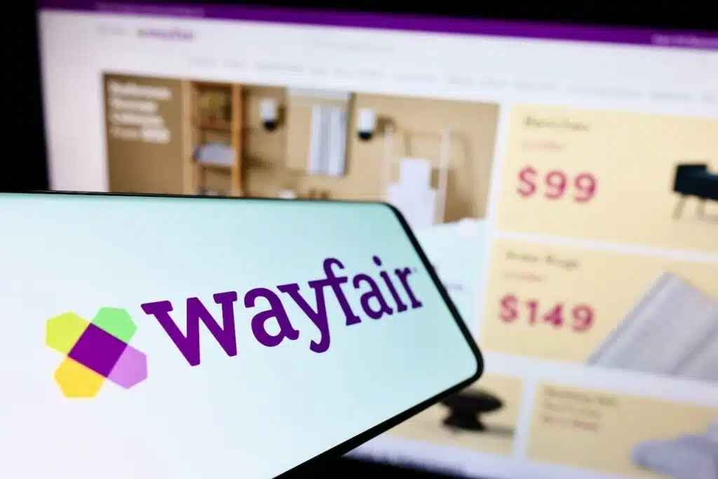 Smartphone with logo of e-commerce company Wayfair Inc. on screen in front of business website.