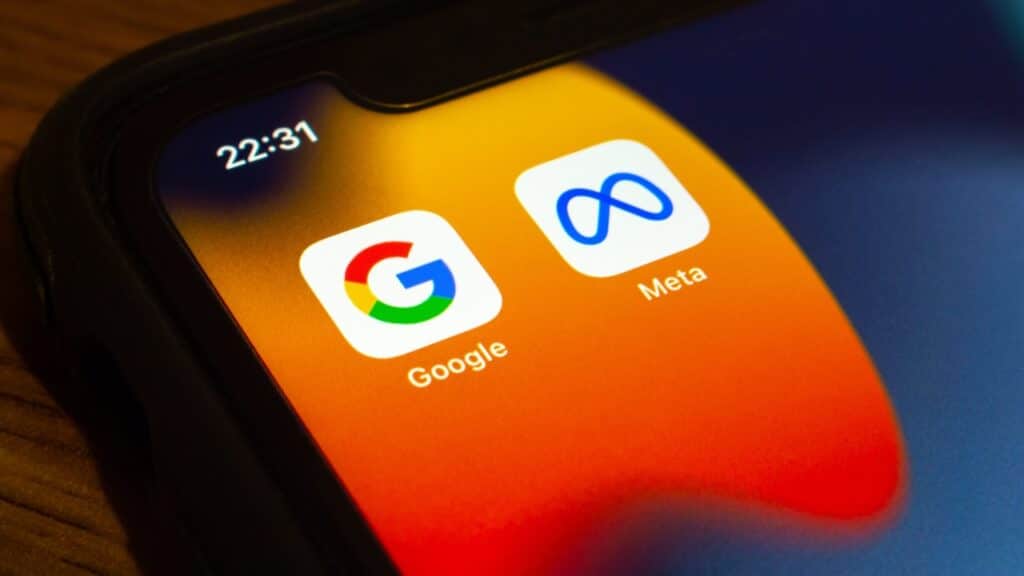 Closeup icons of Google and Meta on an iPhone on wooden table.