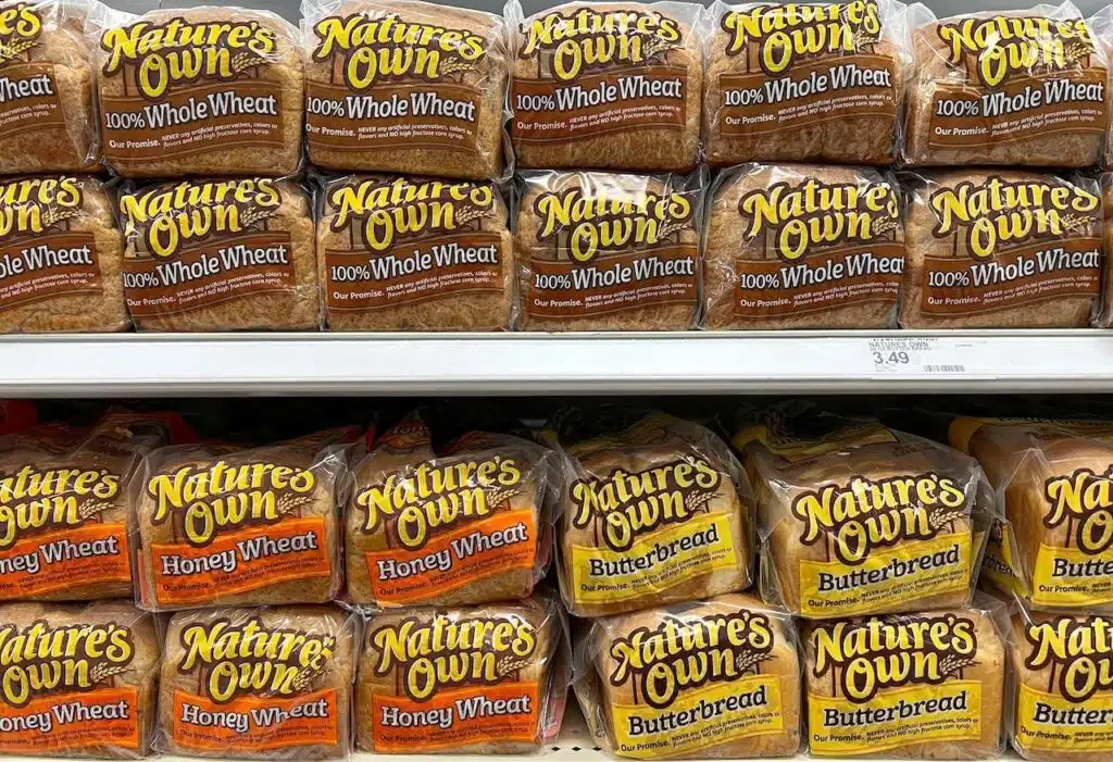 Grocery store shelf with bags of nature's own bread.