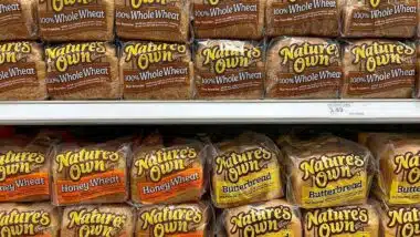 Grocery store shelf with bags of nature's own bread.
