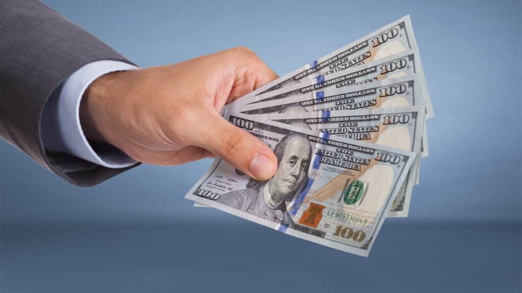 Hand holding paper currency over blue background
