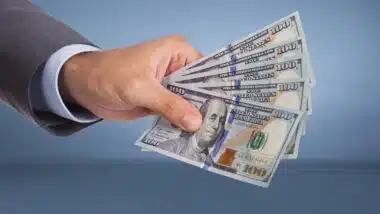 Hand holding paper currency over blue background