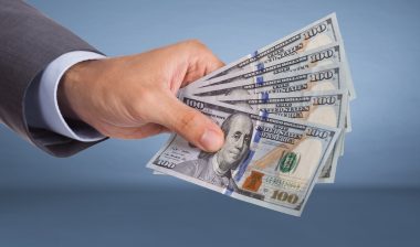 Hand holding paper currency over blue background