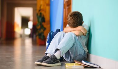 Little boy sitting alone on floor.