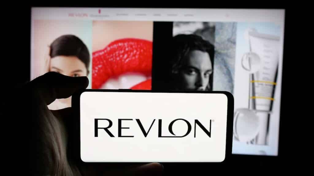 Person holding cellphone with logo of US cosmetics company Revlon Inc.