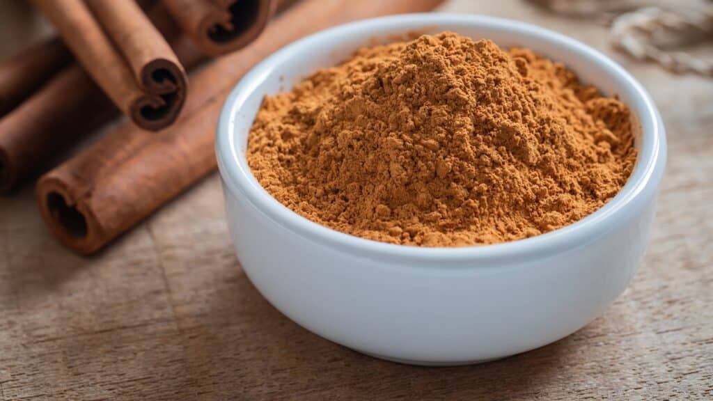 Cinnamon powder and cinnamon sticks on wooden table