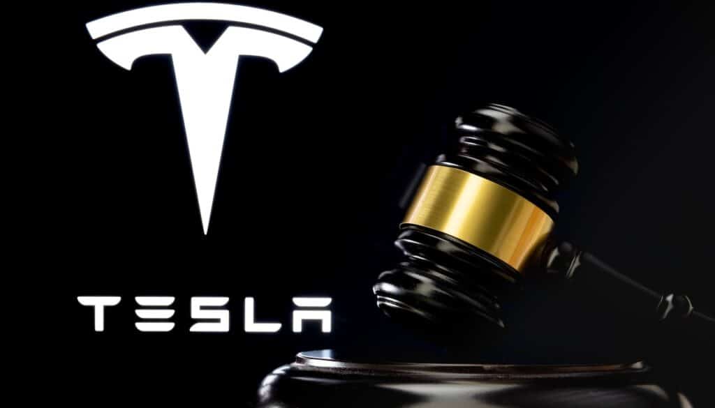 Judge's gavel in front and blurred Tesla Company logo seen on screen behind.