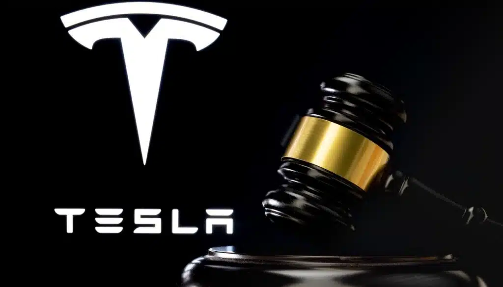 Judge's gavel in front and blurred Tesla Company logo seen on screen behind.