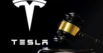 Judge's gavel in front and blurred Tesla Company logo seen on screen behind.