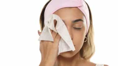 Attractive young woman cleaning her face with a makeup wipe