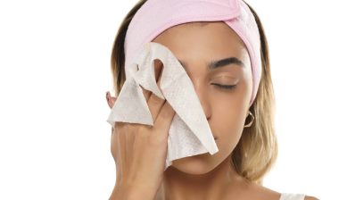 Attractive young woman cleaning her face with a makeup wipe