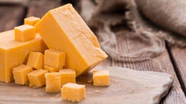 Pieces of Cheddar (close-up shot) on an old wooden table