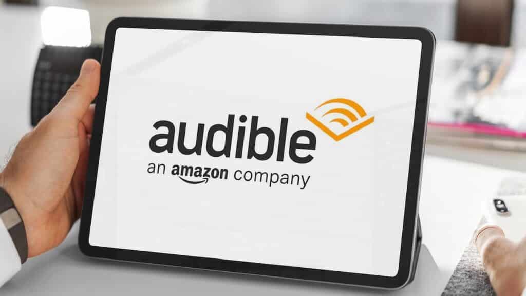 Close-up of businessman using tablet displaying audible logo, amazon's audiobook and podcast service