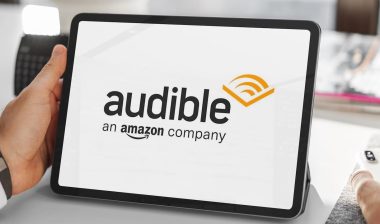 Close-up of businessman using tablet displaying audible logo, amazon's audiobook and podcast service