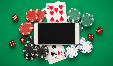 online casino concept, playing cards, dice chips and smartphone with copyspace on the green table. view from above.