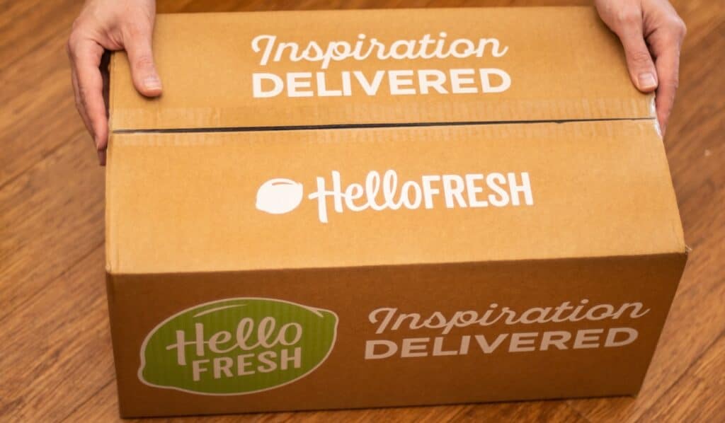 Hands holding Hello Fresh cardbord box with meal kits