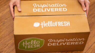 Hands holding Hello Fresh cardbord box with meal kits