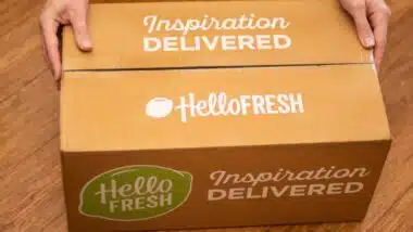 Hands holding Hello Fresh cardbord box with meal kits