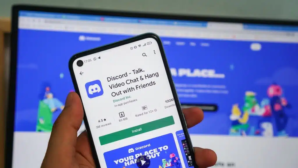 Discord App . Man holding smartphone opens Discord app on smartphone with Discord logo.