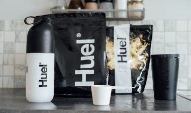 Branded Bags of balanced nutritionally complete meals, shaker and pot from Huel brand on the kitchen table.