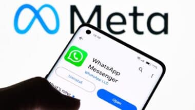 Close-up of a smartphone screen displaying WhatsApp Messenger app with Meta logo in the background