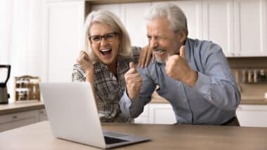 Happy senior spouses looking at laptop screen