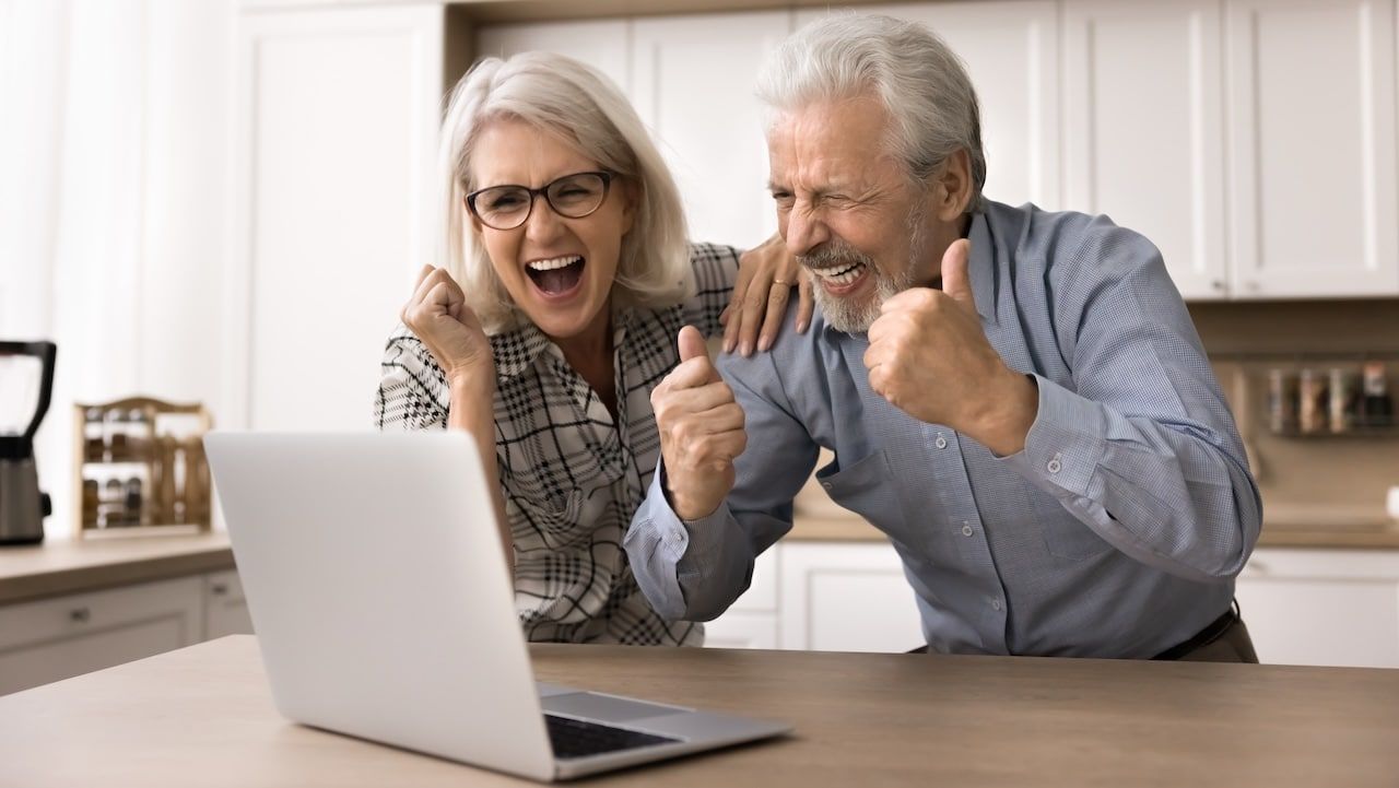 Happy senior spouses looking at laptop screen
