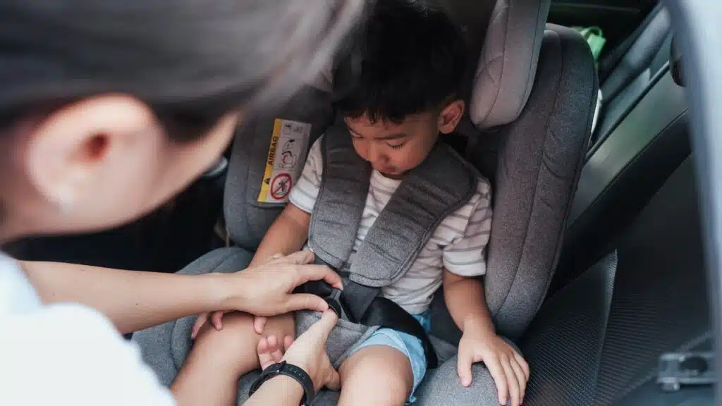 Mom strapping child safely into car seat before departure.