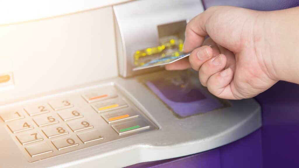 Hand inserting ATM credit card into bank machine