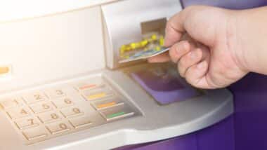 Hand inserting ATM credit card into bank machine