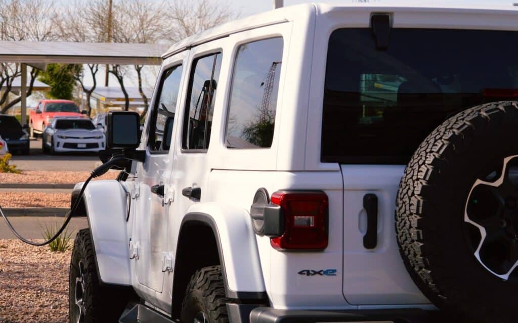 A Jeep Wrangler Rubicon unlimited 4xe gas electric plug-in hybrid model plugged in and charging