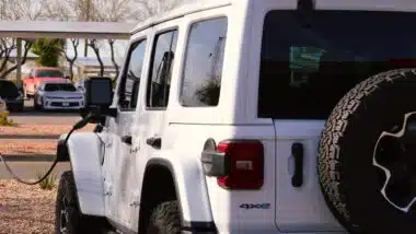 A Jeep Wrangler Rubicon unlimited 4xe gas electric plug-in hybrid model plugged in and charging