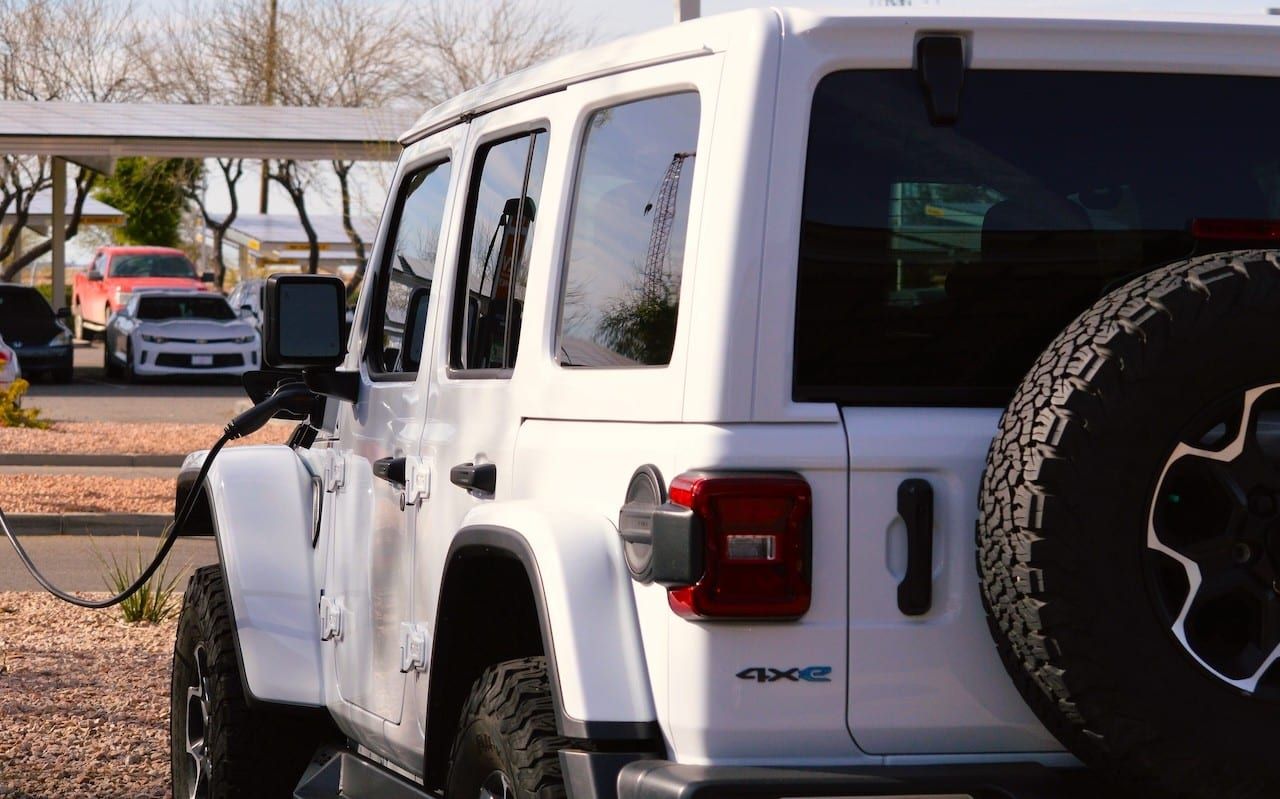 A Jeep Wrangler Rubicon unlimited 4xe gas electric plug-in hybrid model plugged in and charging