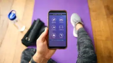 Close Up Of Woman With Smart Watch About To Exercise Looking At Activity Tracker On Mobile Phone