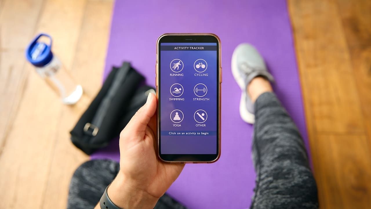 Close Up Of Woman With Smart Watch About To Exercise Looking At Activity Tracker On Mobile Phone