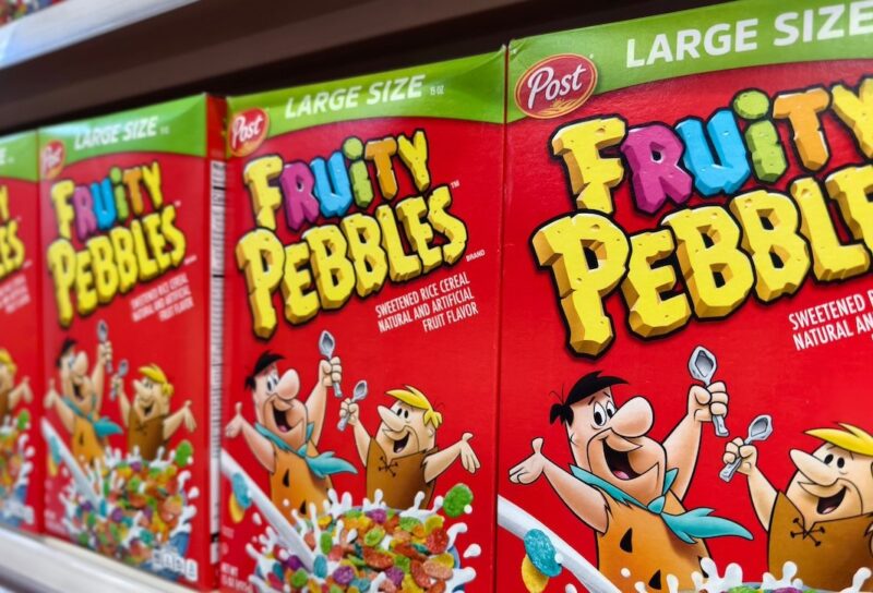 Close-up of multiple Fruity Pebbles cereal boxes on a supermarket shelf.