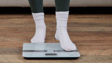 A young woman stands on a scale in her home,