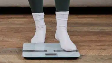 A young woman stands on a scale in her home,