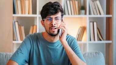 Skeptic dissatisfied shocked puzzled man speaking on phone in modern home