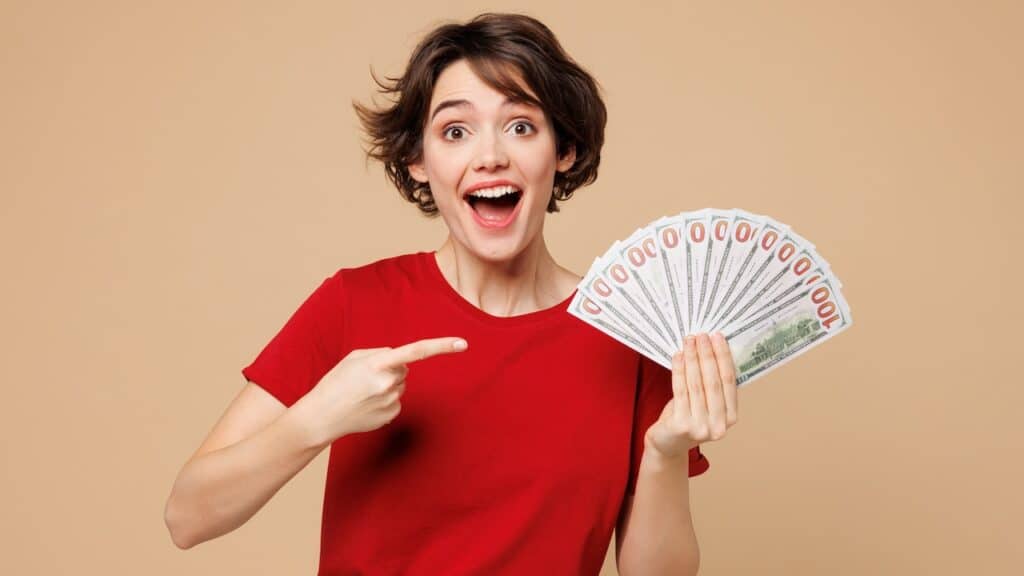 Young smiling happy woman she wearing red t-shirt casual clothes hold in hand fan of cash money