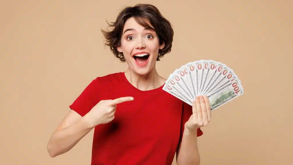 Young smiling happy woman she wearing red t-shirt casual clothes hold in hand fan of cash money