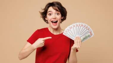 Young smiling happy woman she wearing red t-shirt casual clothes hold in hand fan of cash money