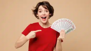 Young smiling happy woman she wearing red t-shirt casual clothes hold in hand fan of cash money