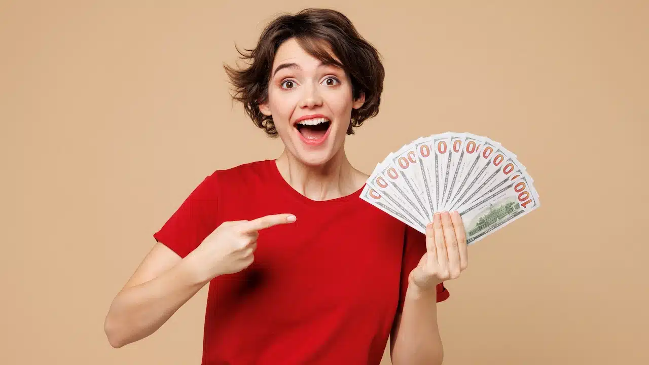 Young smiling happy woman she wearing red t-shirt casual clothes hold in hand fan of cash money