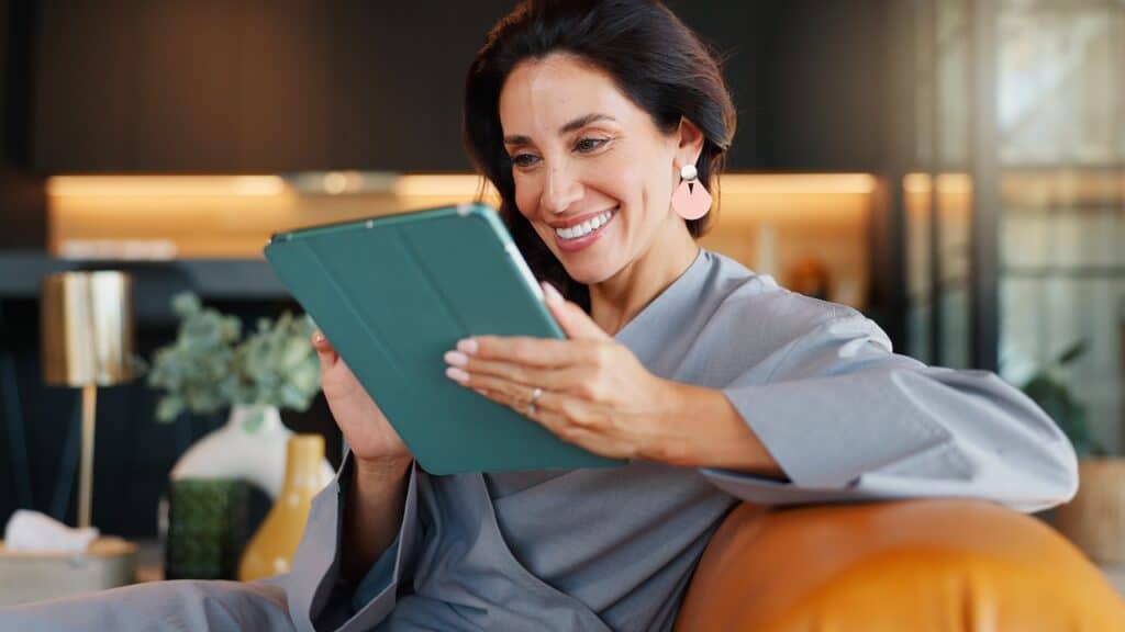 Online booking, smile and tablet with woman in spa for appointment or schedule. Agenda, hospitality and wellness with happy person checking calendar in luxury beauty salon for cosmetic treatment