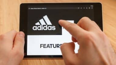Close up to hands holding tablet using internet and looking through adidas web site