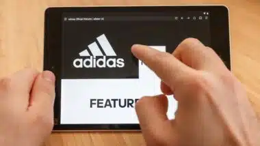 Close up to hands holding tablet using internet and looking through adidas web site